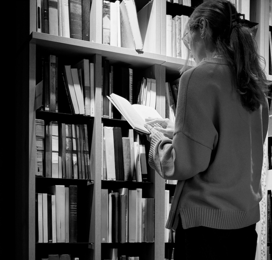 A person standing in front of library shelves reading a book